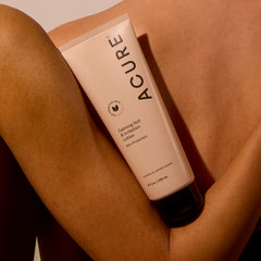 Tube of Calming Itch and Irritation Lotion resting on a woman's arm, supported by the back of another woman, highlighting skin-soothing care