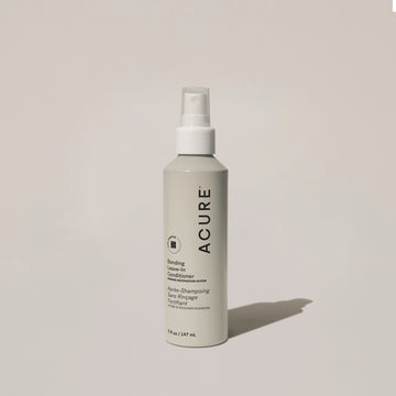 A bottle of ACURE Bonding Leave-In Conditioner spray on a neutral background.
