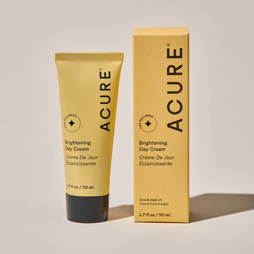 Brightening day cream tube next to its packaging on a neutral background