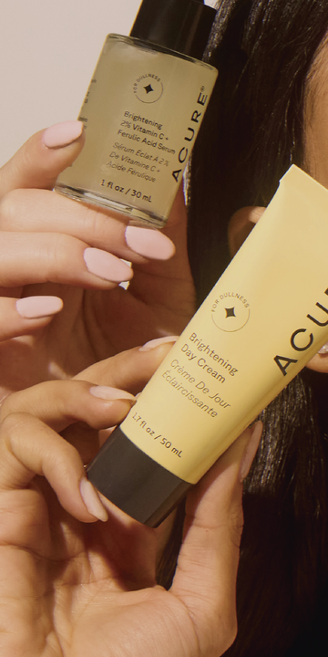 Close-up view of women's hand holding Acure's vegan skinccare products focusing on glowing, healthym hydrated, smooth skin