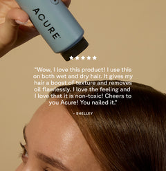 Background of a Woman applying Acure dry shampoo - customer review: "Wow I love this product! I use this on both wet and dry hair. It gives my hair a boost of texture and removes oil flawlessly. I love the feeling and I love that it is non-toxic! Cheers to you Acure! you nailed it! " - Shelley