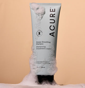 Simply Smoothing Shampoo tube with airy foam surrounding the tube, evoking a fresh, just-lathered feeling."