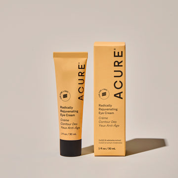 A tube of ACURE Radically Rejuvenating Eye Cream next to its packaging labeled ACURE