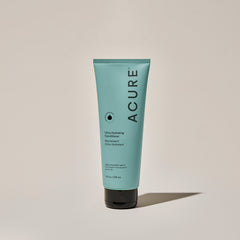 A tube of ACURE Ultra Hydrating Conditioner against a neutral background.