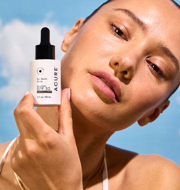 Woman holding Acure sunscreen – clean, reef-safe sun protection with a radiant finish