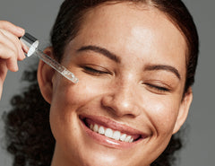 Woman applying a skincare product to her face with a dropper.