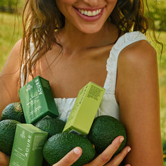 Woman holding green avocados and Acure boxes outdoors