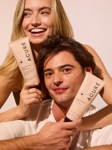 Two people holding Acure skincare products against a neutral background