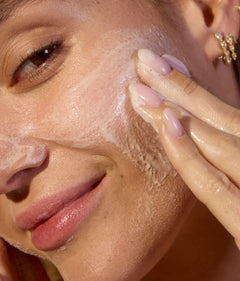 Woman applying Acure cleanser to her face focusing on brightened and clean skin