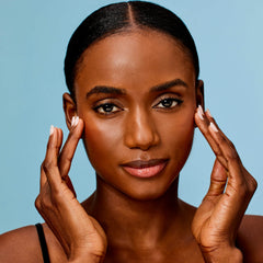 Woman applying cream to her face against a blue background