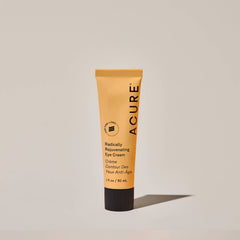 Acure Radically Rejuvenating Eye Cream tube on a beige background