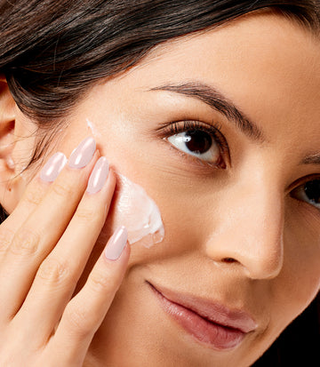 Woman applying face moisturizer