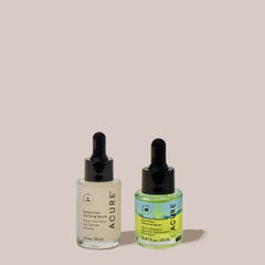 Two Acure skincare serum bottles with droppers on a beige background including Zombie Cell clarifying serum and Radically Rejuvenating Dual Phase Bakuchiol Serum