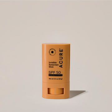 Acure Invisible Sunscreen Stick SPF 50 in a yellow twist-up tube, standing upright on a neutral background.