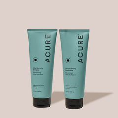 Two bottles of Acure Ultra Hydrating Shampoo and Conditioner on a beige background