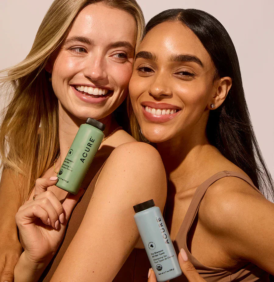 Two women holding Acure's dry shampoos