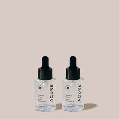 Two Acure skincare serum bottles with droppers on a light pink background