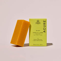 Bar of soap and its packaging on a light pink background