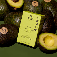 Acure avocado oil and lavender soap bar with avocados in the background