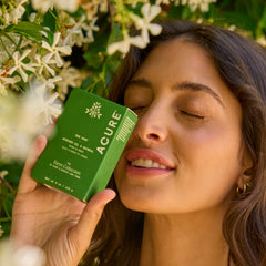 Woman holding an Acure product with a floral background