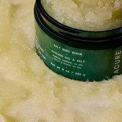 Green jar of Acure Salt Body Scrub with scrub visible on top