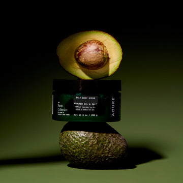 Avocado body scrub jar with half an avocado on a dark green background