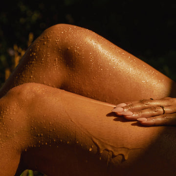 Close-up of a person's legs with oil and water droplets on a dark background