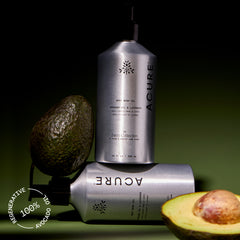 Acure body wash bottles with an avocado on a green background