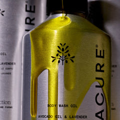 Bottle of Acure body wash oil with a black logo on a blurred background