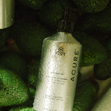 Acure Farm collection body wash oil bottle on a green avocado background