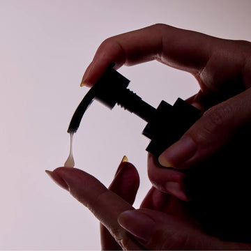 Person holding a bottle with pump with a white background