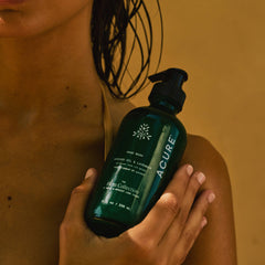 Person holding a bottle of Acure hand wash against a warm-toned background