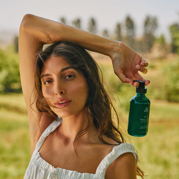 Woman holding a hand wash bottle outdoors in a natural setting