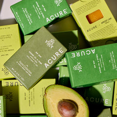 Acure soap bars and packaging with an avocado on a light background