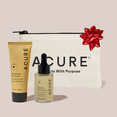 Acure skincare products with a pouch and red bow on a light background