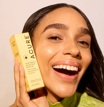 Woman smiling, holding a box of Ultra Hydrating 12 Hour Facial Moisturizer next to her face