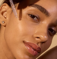Woman applying Zombie Cell Clarifying Serum with a dropper on her cheek