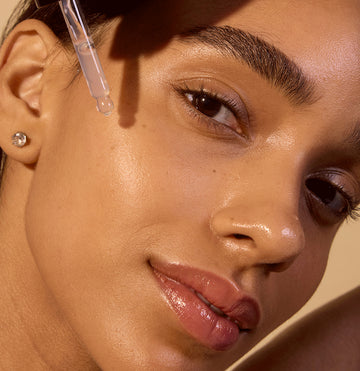 Woman applying Zombie Cell Clarifying Serum with a dropper on her cheek