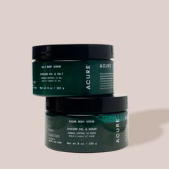 Two jars of Acure body scrub on a beige background
