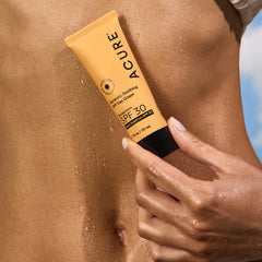Person applying Acure sunscreen on their arm with a clear background