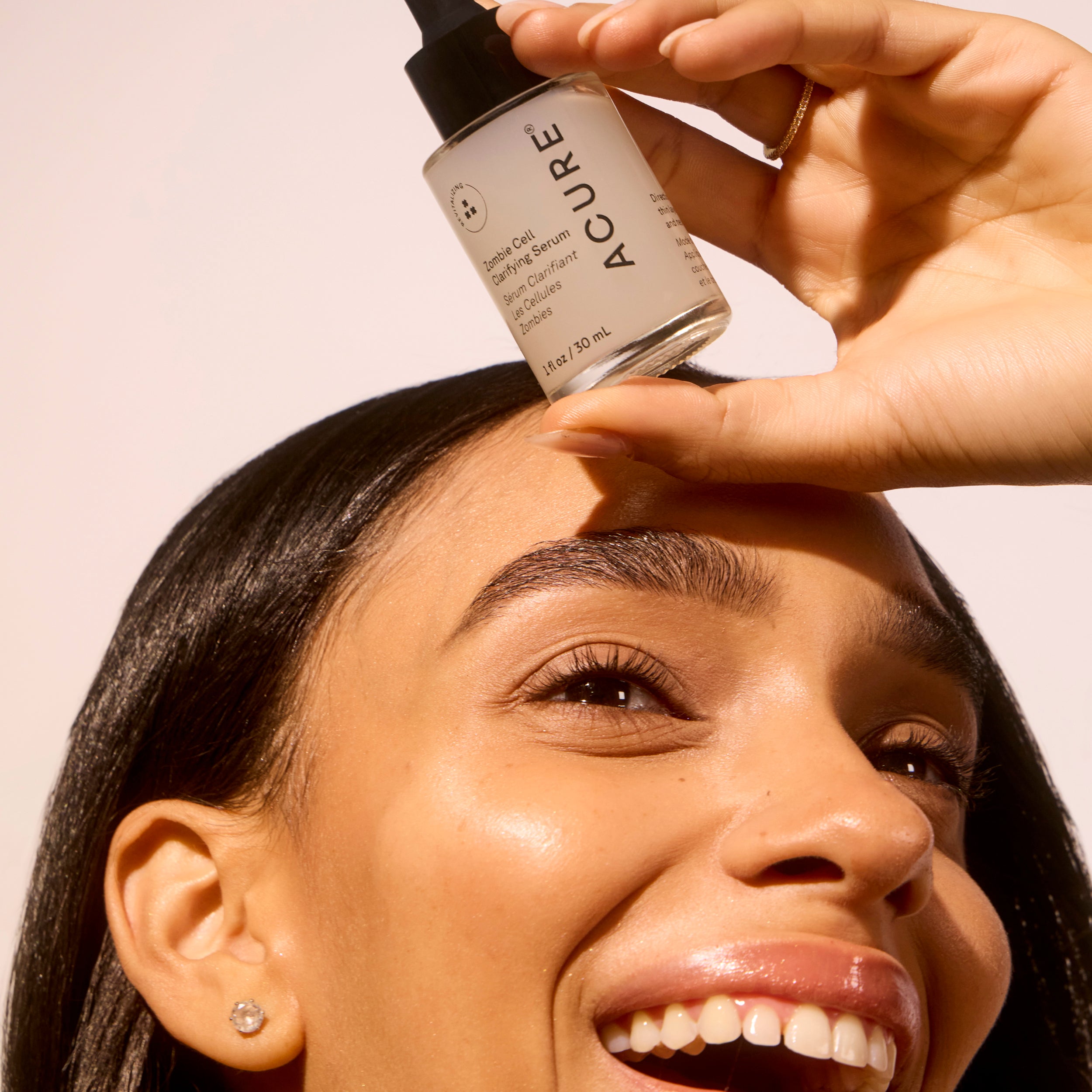 Woman holding next to her face a jar of Zombie Cell Clarifying Serum