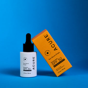 Sunscreen SPF 30 Sun Serum Drops bottle next to its backaging on a blue background