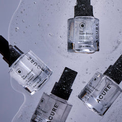 Acure skincare droppers on a textured gray background