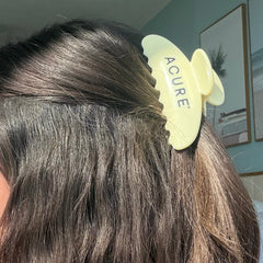 Acure hair product on a person's head with a blurred indoor background