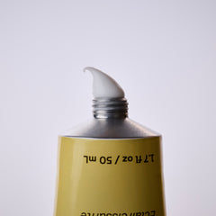 Gold tube of cream with a white cap on a light gray background
