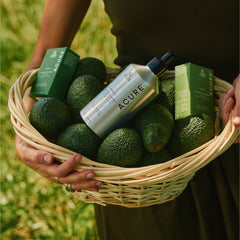 Person holding a basket with avocados and Acure products outdoors