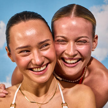 Two women smiling with a clear blue sky in the background