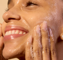 Close-up of a woman applying a skincare product to her face.