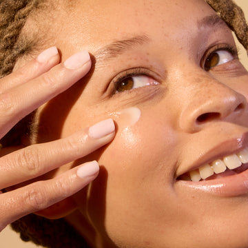 Woman applying eye balm on her under eye area