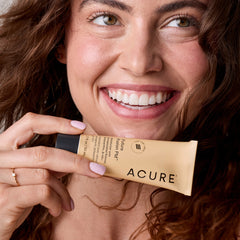 Woman holding a tube of Acure skincare product